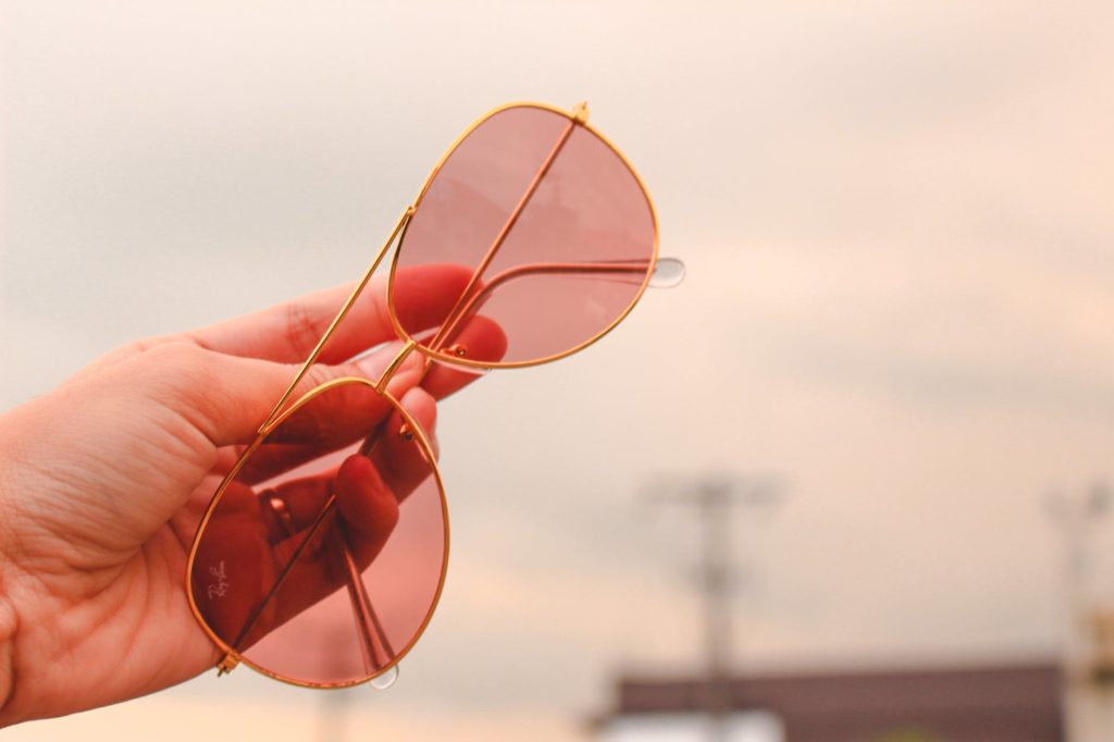a picture of a hand holding aviator sunglasses