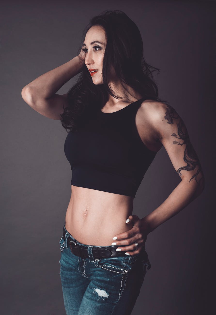 a woman wearing a cropped halter top with blue jeans