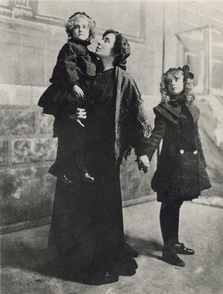 Mary Robinson McConnell (Mary Gish) carrying her daughter Dorothy Gish and holding her older daughter Lillian Gish by the hand in front of theatrical scenery
