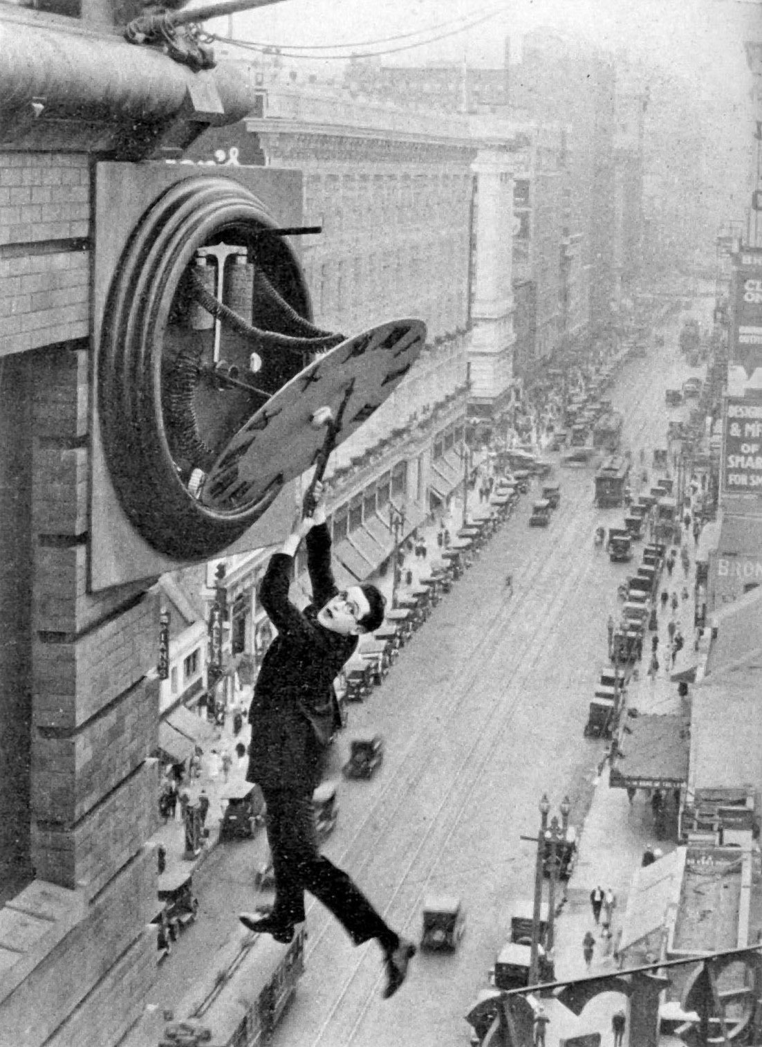An iconic scene from the film “Safety Last!” where Harold Lloyd is seen hanging from a clock hand on top of a skyscraper.