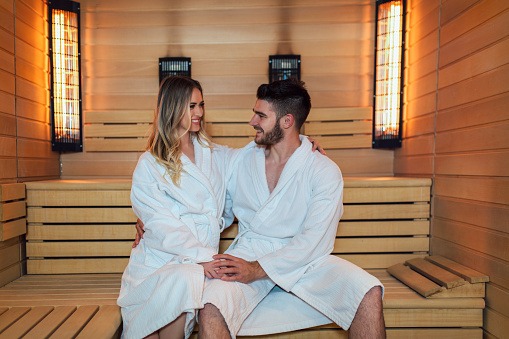 Healthy beautiful couple relaxing in infrared sauna during wellness weekend
