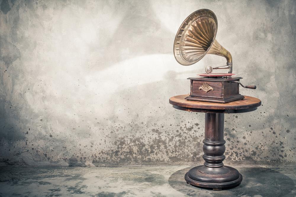 Antique gramophone phonograph turntable with brass horn and red color vinyl disc record on wooden table