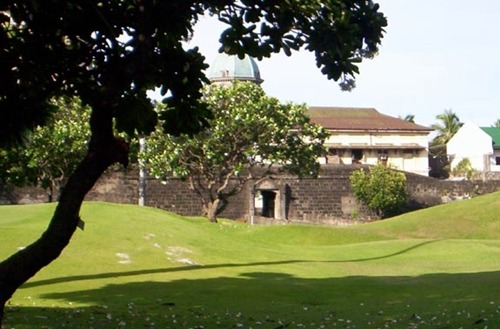 <EM>Postigo del Palacio </EM>today: the pathway leading from the gate has been covered over by parts of a golf course. The dome of the Manila Cathedral is seen in the background.