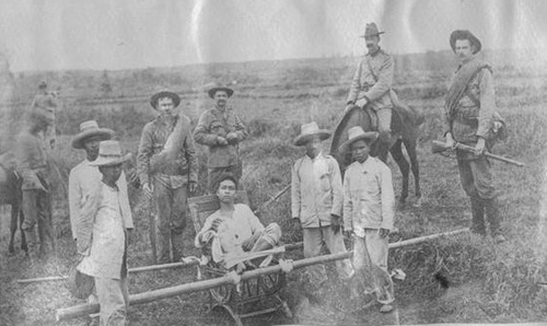 Wounded Filipino being carried by Filipino POWS to 1st Colorado hospital, 1899