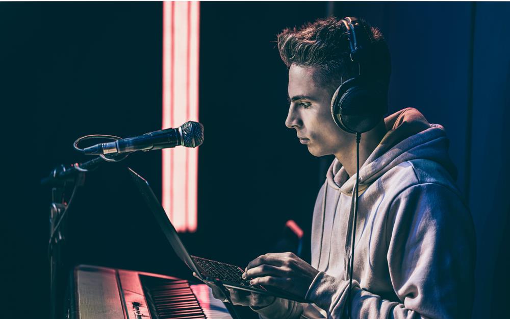 Man in headphones behind the musical keys with a laptop