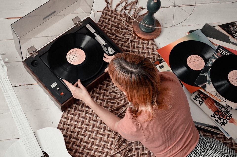woman lying on the floor and playing a vinyl record in a record player