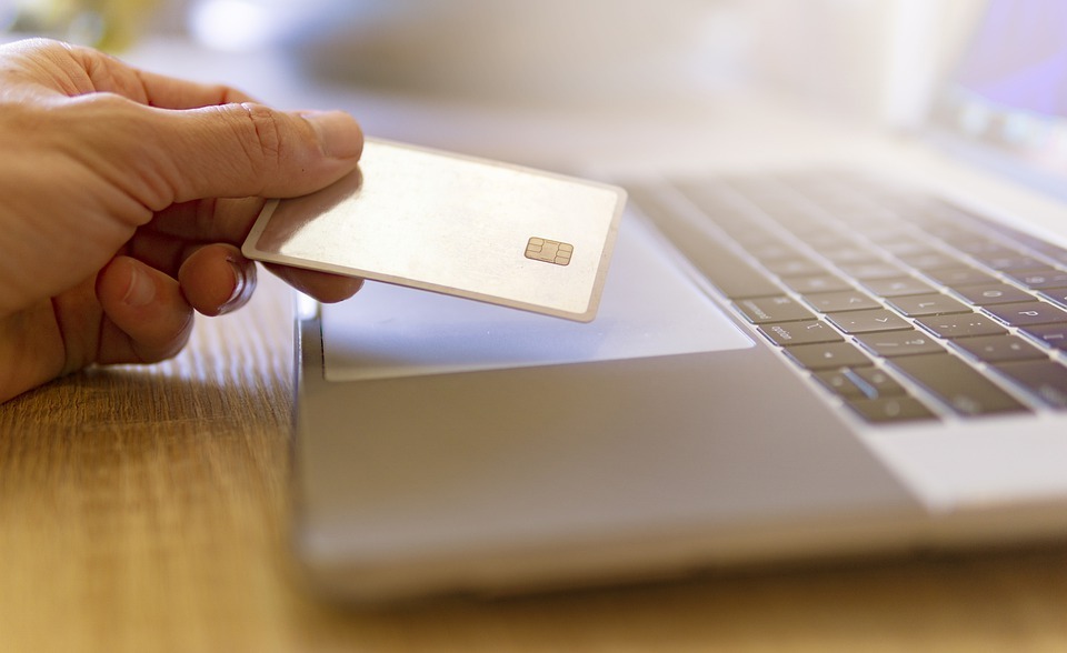 person holding a credit card in front of a laptop