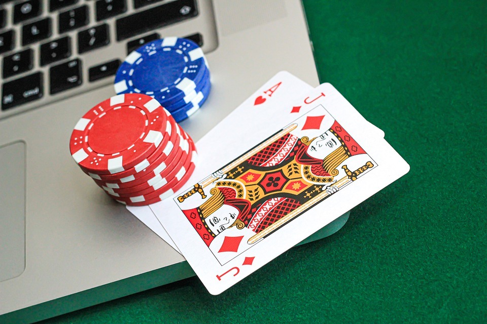poker cards and chip on top of a laptop keyboard)