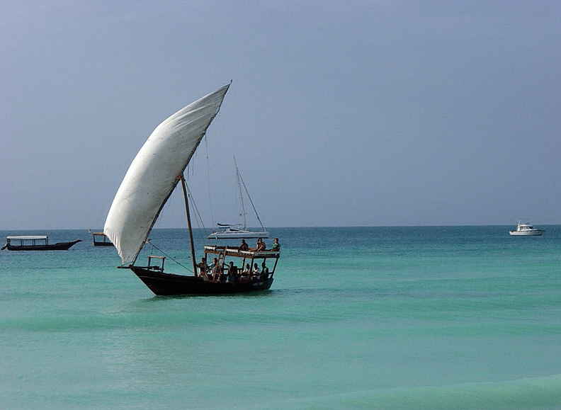 a large dhow with lateen sail rigs in blue waters