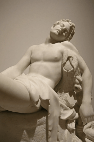 A classic stone sculpture of a resting man 