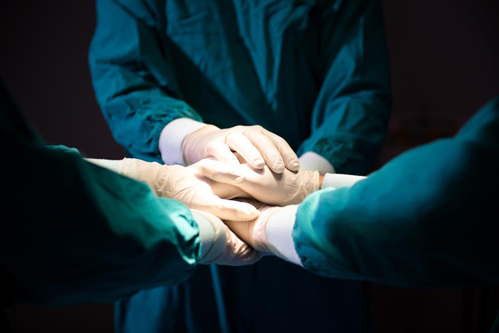 Doctors joining hands before an operation