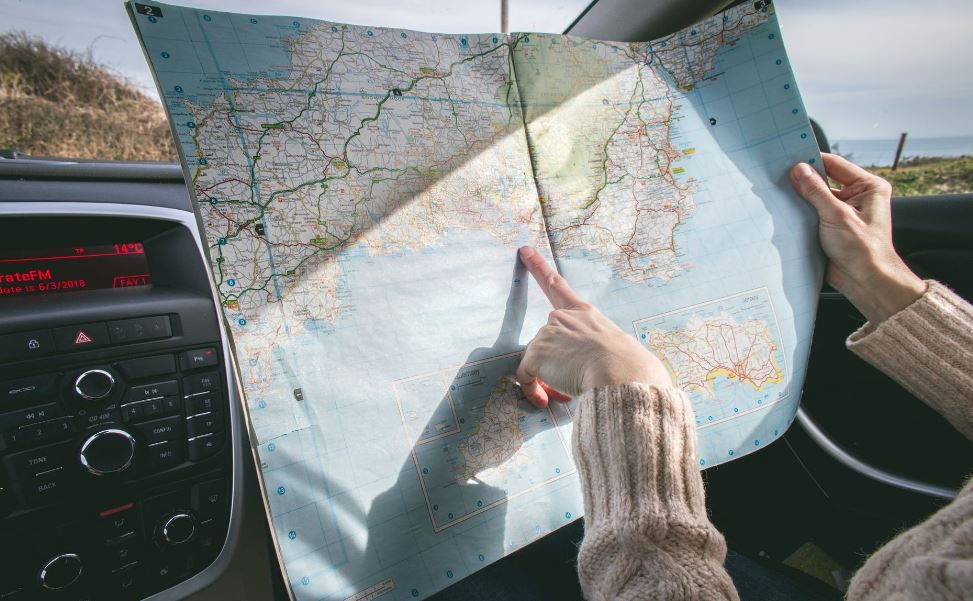 a person wearing a beige sweater holding a map inside the car