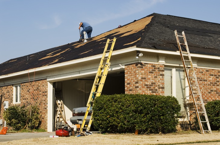Man on a rooftop repairing tornado damaged shingles