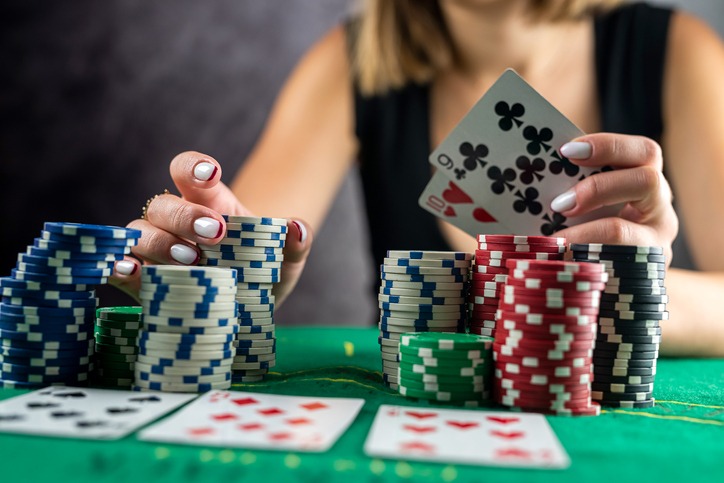 Female hand taking poker chips from pile at round poker table.