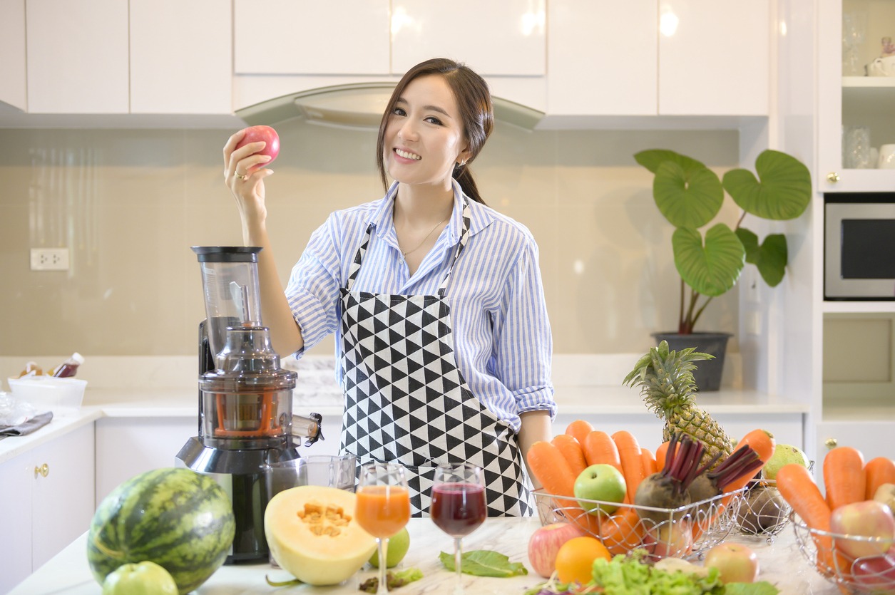 woman juicing fresh fruits and vegetables