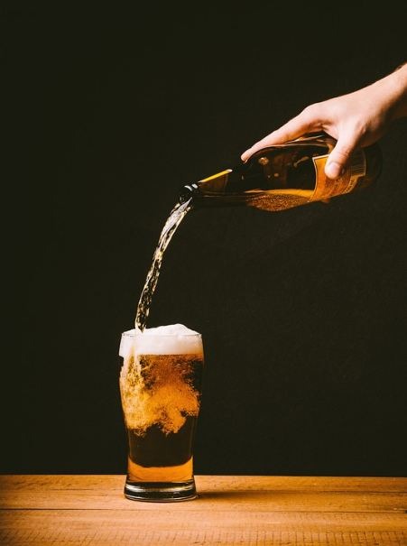 a-hand-pouring-a-bottle-of-beer-into-a-glass