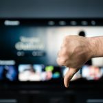Bad movie. Film critic watching tv. Thumbs down, dislike. Stream service. Cancel subscription. Negative feedback. Video on demand, VOD. Television series and film site online with expensive price